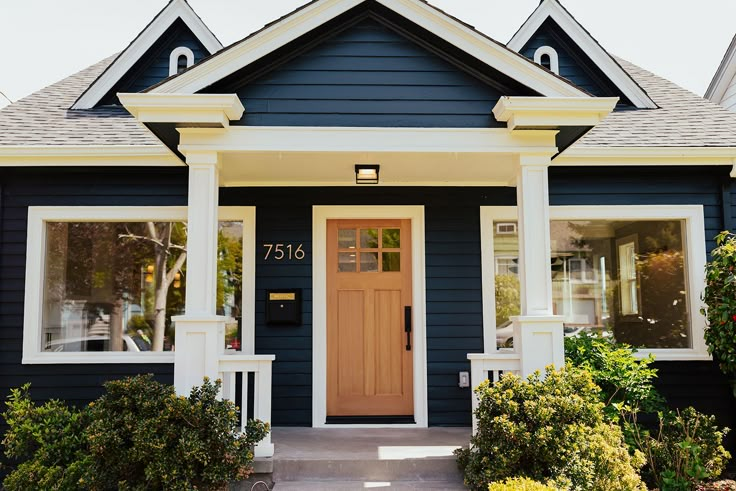 a blue house with white trim and two large windows on the front door is shown