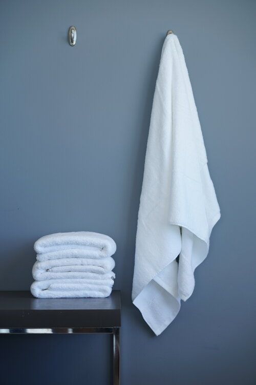 a stack of white towels sitting on top of a table next to a towel rack