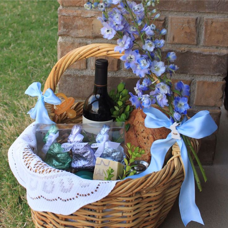 a wicker basket filled with wine bottles and chocolates next to a brick wall