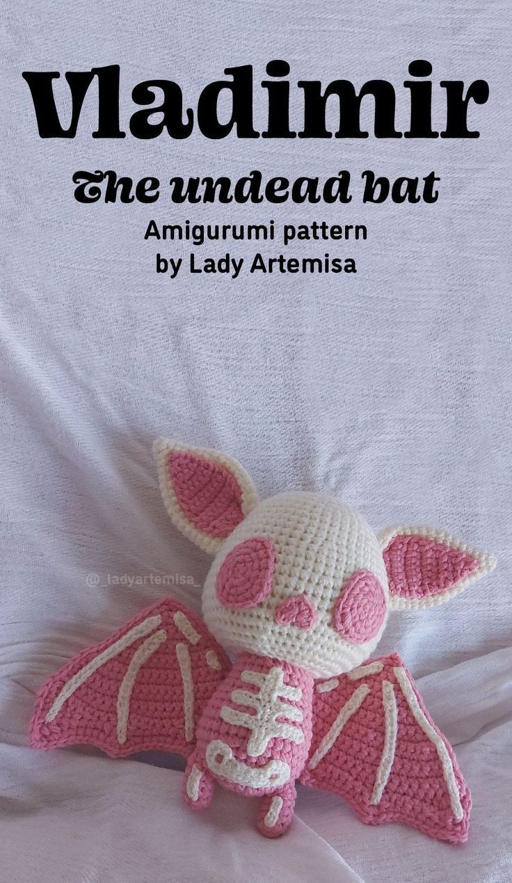 a crocheted pink bat laying on top of a white sheet