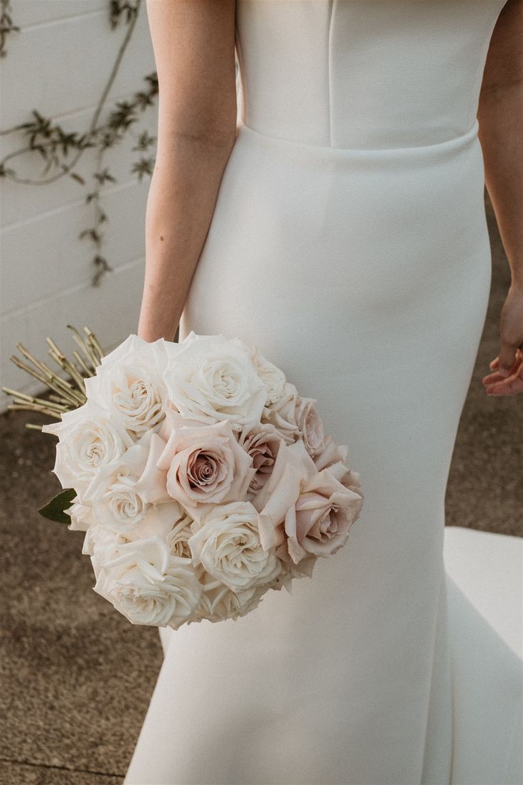 a woman in a white dress holding a bridal bouquet