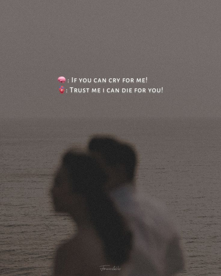 a couple standing next to each other in front of the ocean with an overcast sky