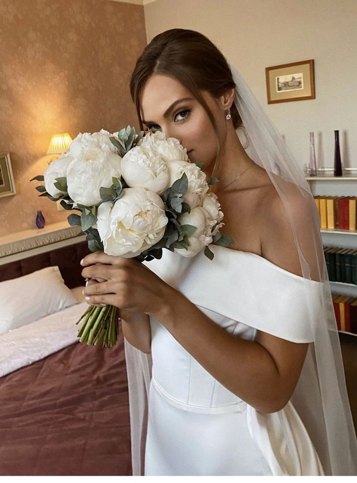 a woman in a wedding dress holding a bouquet of flowers