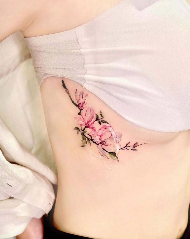 a woman's stomach with pink flowers on the side and behind her is a white shirt