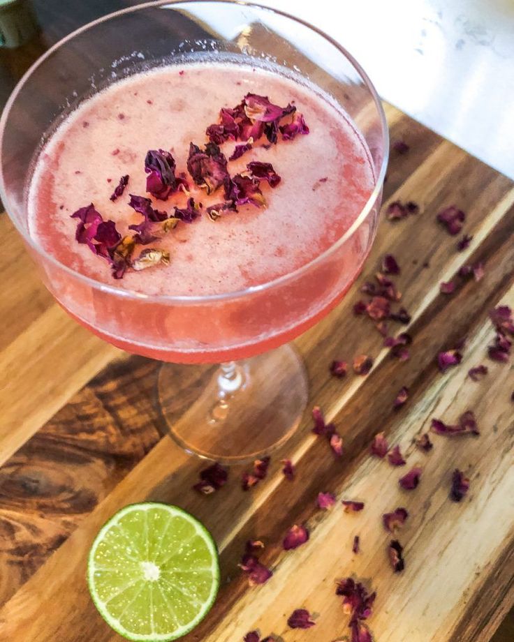 a drink in a wine glass with garnishes on the rim next to a slice of lime