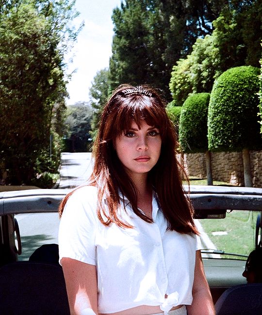 a woman sitting in the back of a car with her hands on her hips and looking at the camera