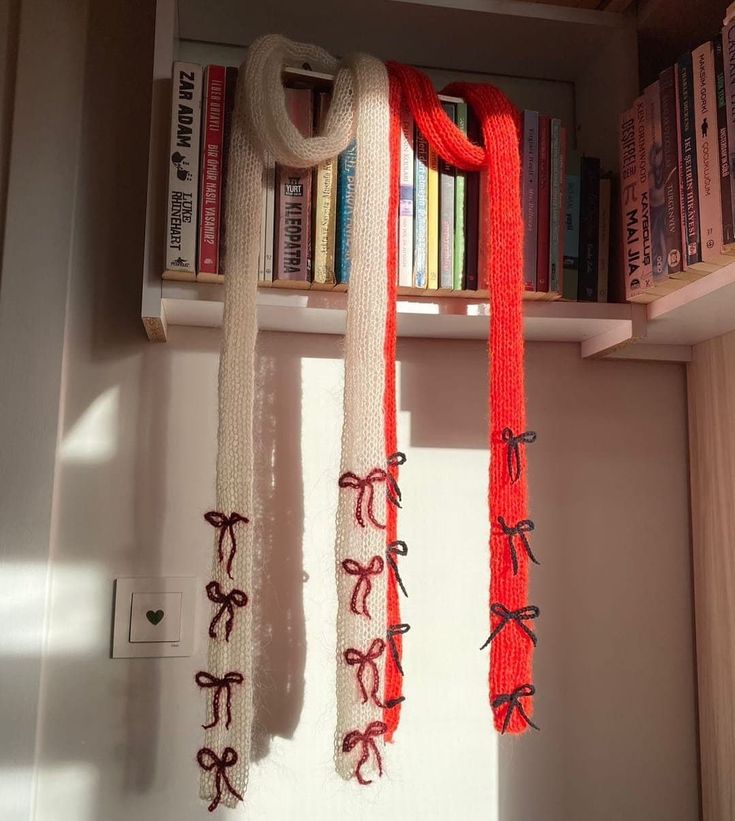 two red and white scarfs hanging from a book shelf