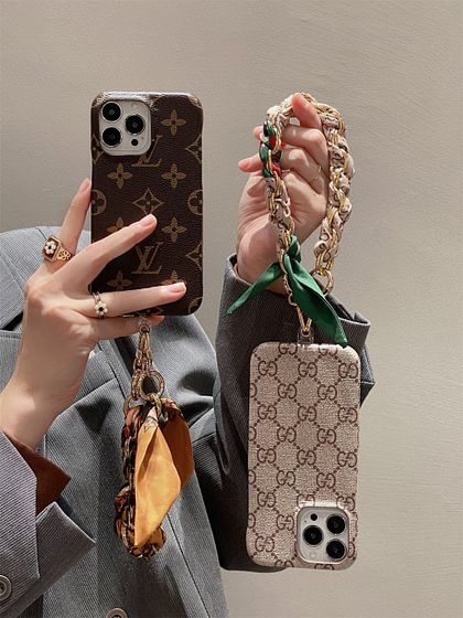 a woman holding two cell phones in her hands and one with a chain attached to it