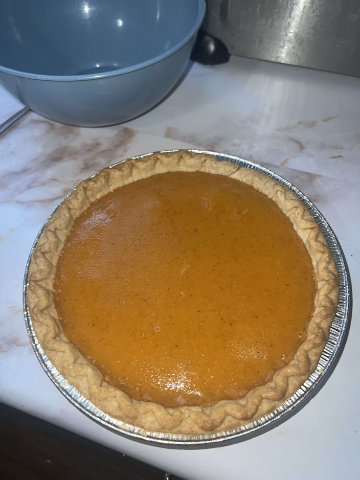 a pie sitting on top of a counter next to a bowl