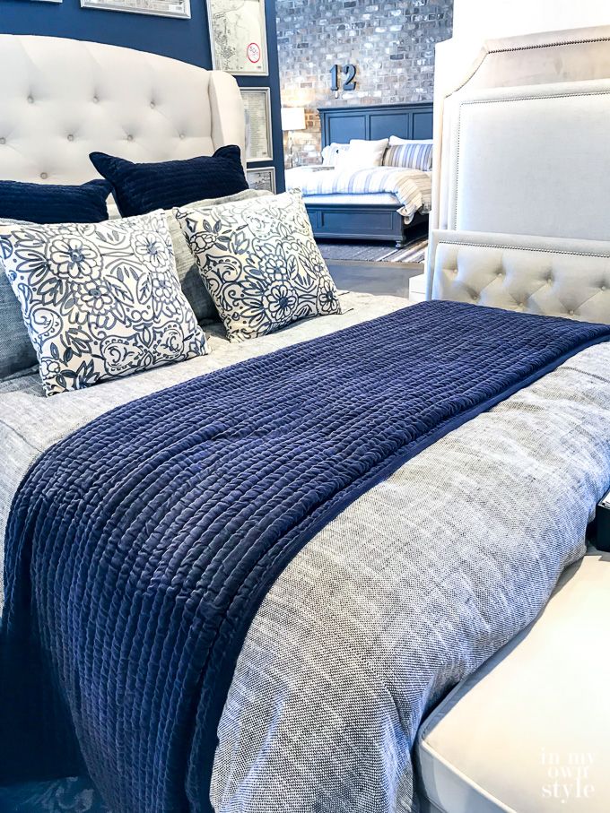 a bed with blue and white pillows in a store display room at the furniture showroom