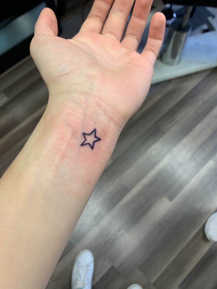 a person's hand with a small star tattoo on it