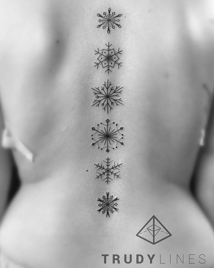 the back of a woman's neck with snowflakes tattooed on her ribs