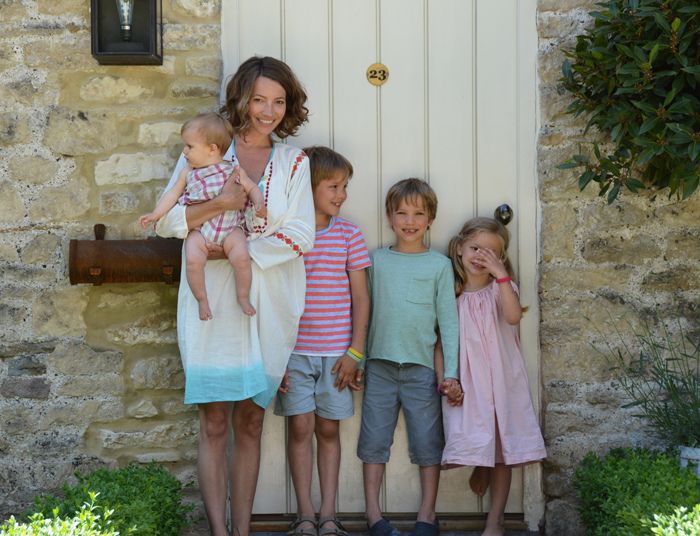 a woman standing next to three children in front of a door