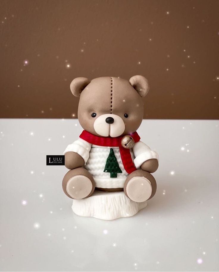 a brown teddy bear sitting on top of a white table next to a christmas tree