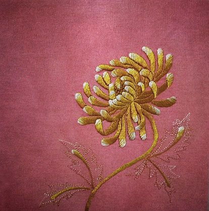 a close up of a flower on a pink background with gold threadwork and sequins