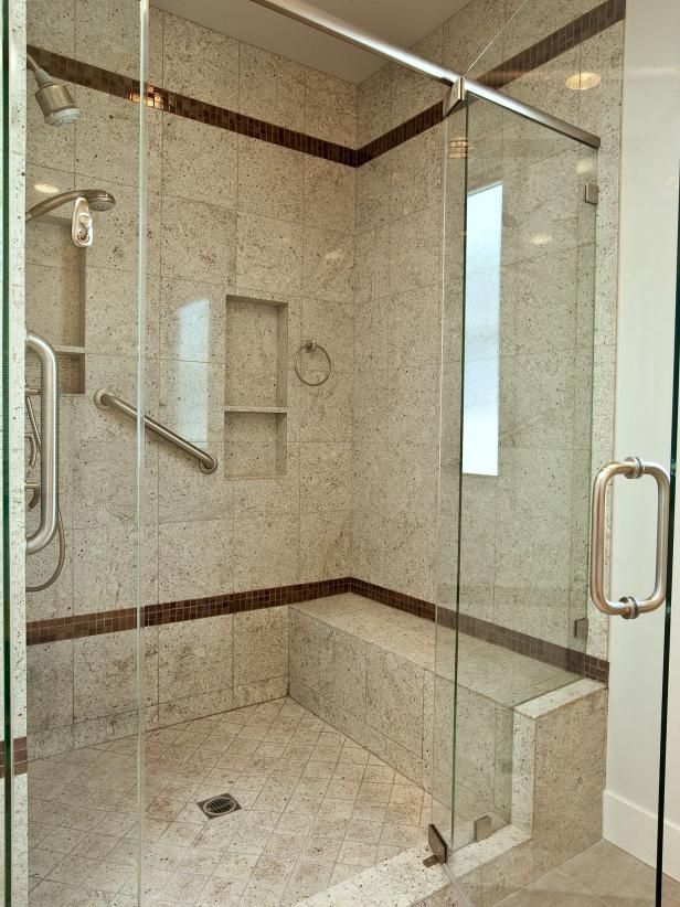 a walk in shower sitting next to a glass door and window on top of a tiled floor