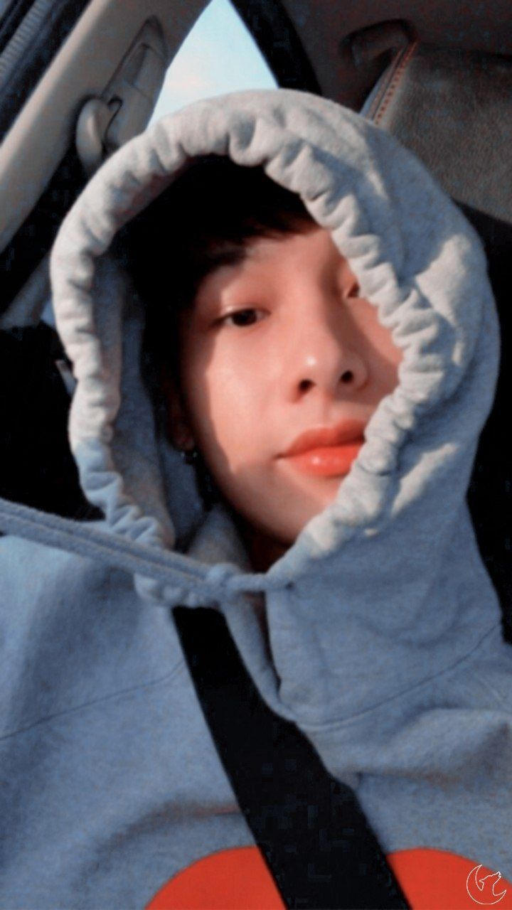 a young boy sitting in the back seat of a car wearing a blue hoodie