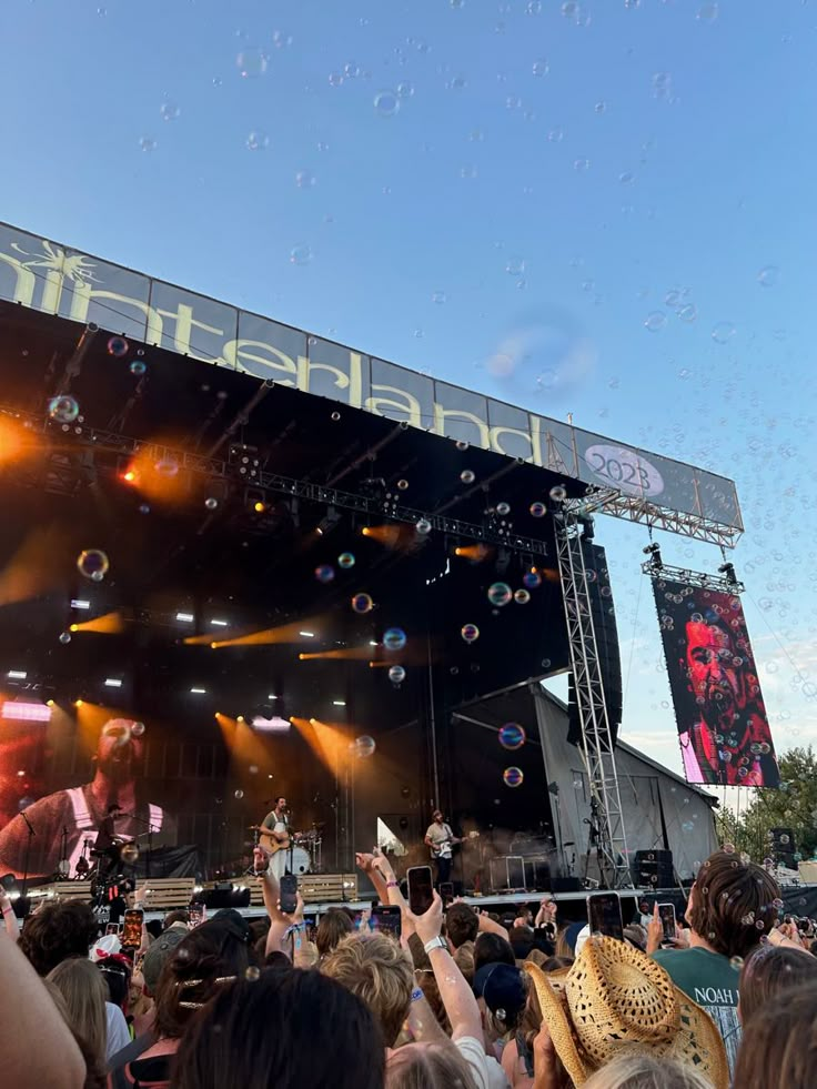 a group of people standing on top of a stage with bubbles flying in the air