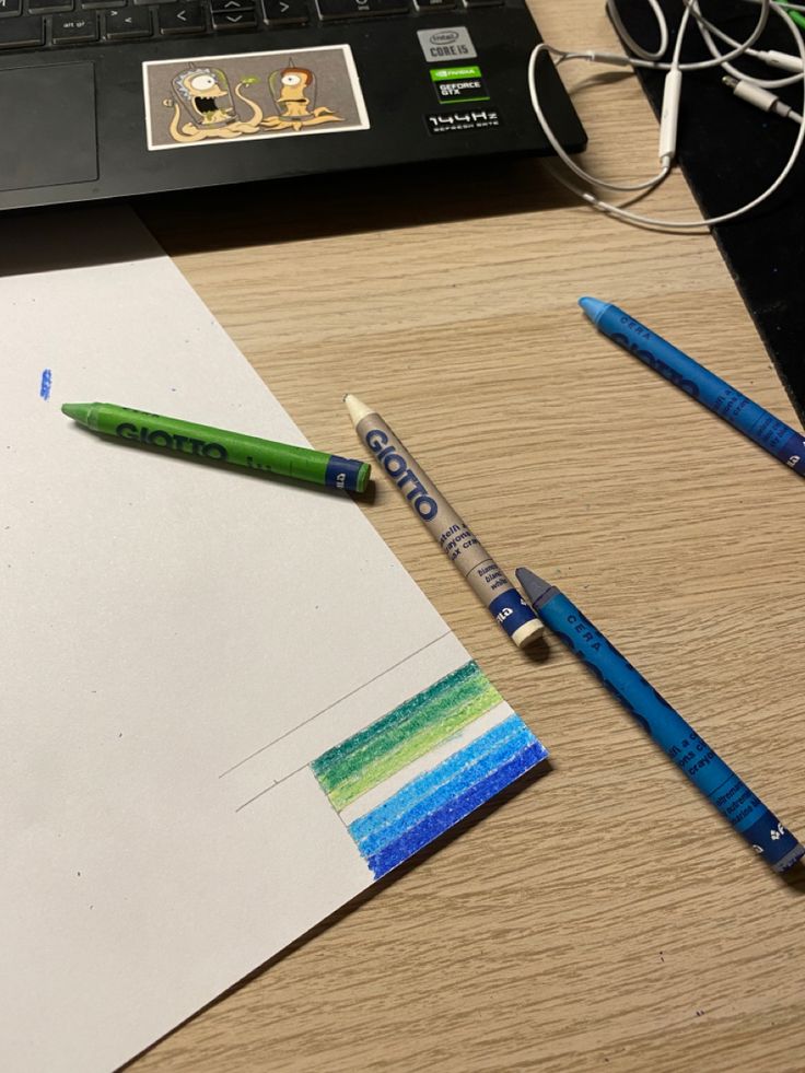 two crayons are sitting on top of a piece of paper next to a laptop