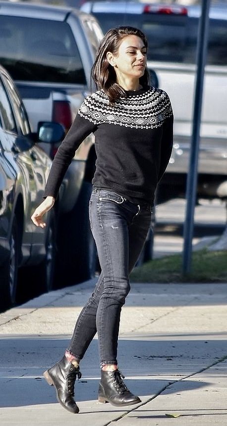 a woman is walking down the street in her black sweater and jeans, while wearing ankle high boots