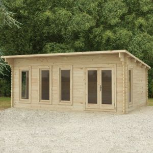 a small wooden building sitting on top of a gravel field next to some green trees