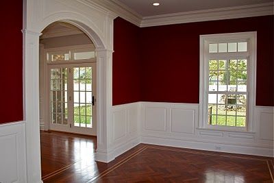 an empty room with red walls and white trim on the windows, wood floors and hard wood flooring