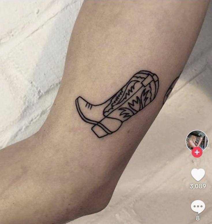 a tattoo on the leg of a person with a cowboy boot and flowers in it