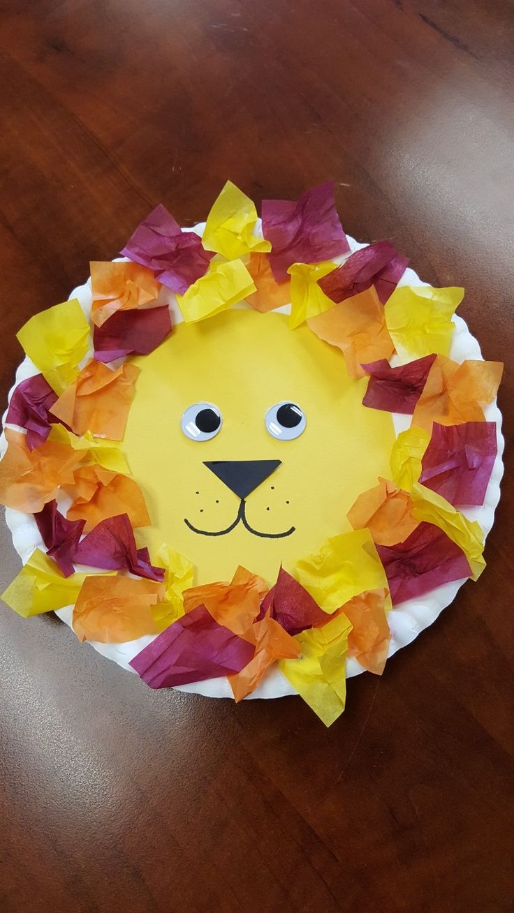 a paper plate with a lion's face made out of orange and yellow tissue paper