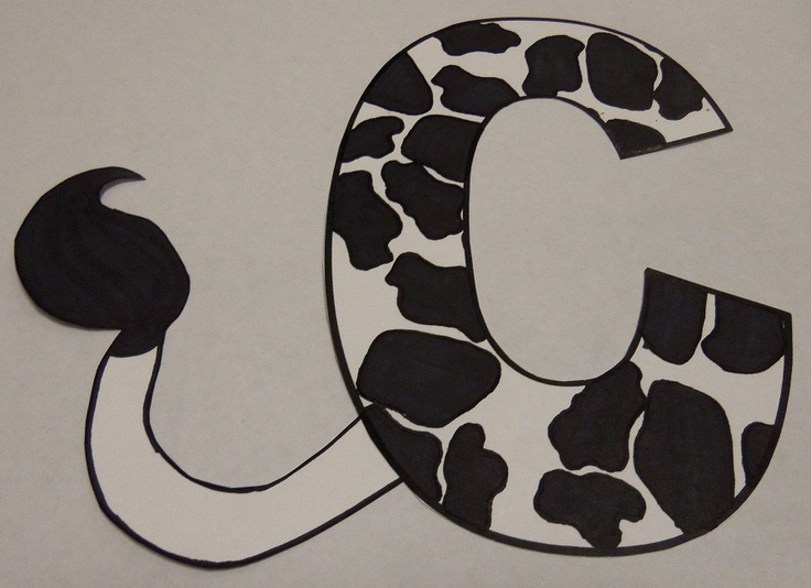 the letter c is made up of black and white cow print paper, with an animal's tail sticking out of it