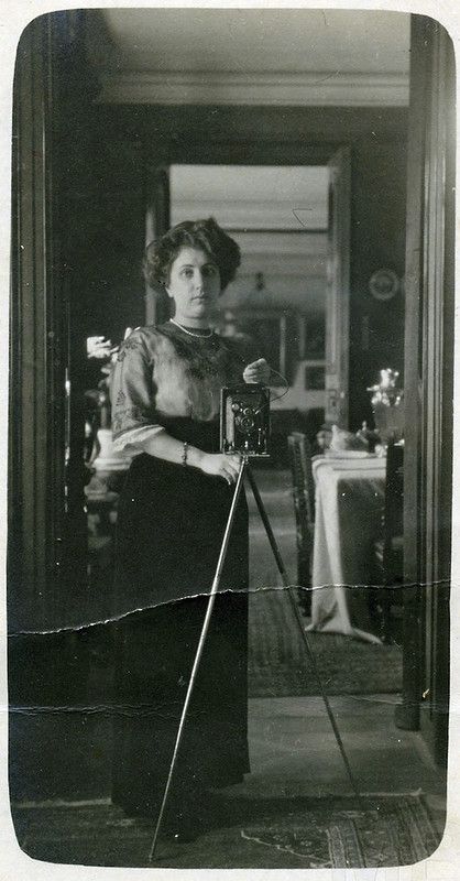 an old black and white photo of a woman holding a camera