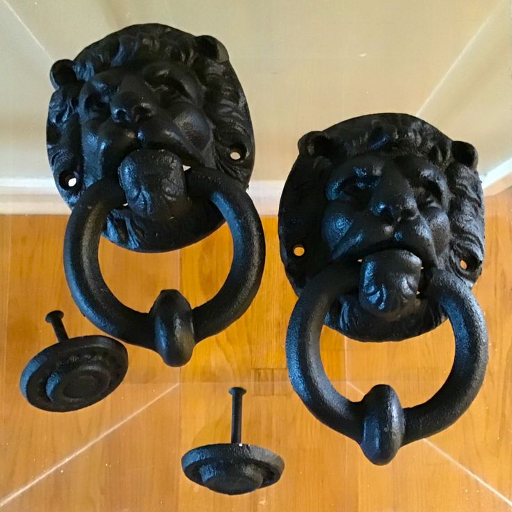 two black iron lion head door handles on a wooden floor