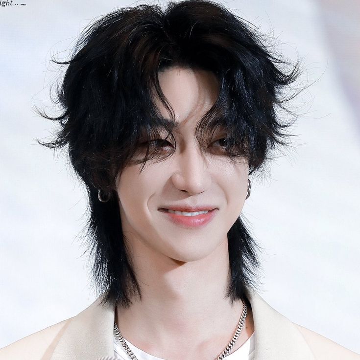 a close up of a person with black hair wearing a white shirt and necklace on his neck