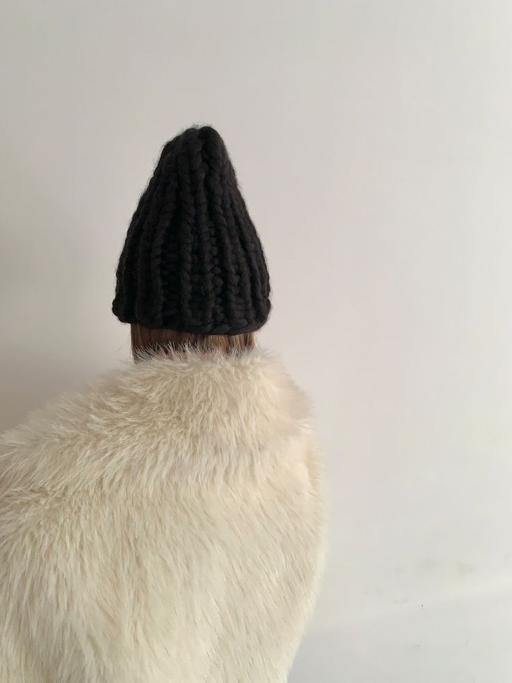 a white fur coat with a black knitted hat on it's head and back