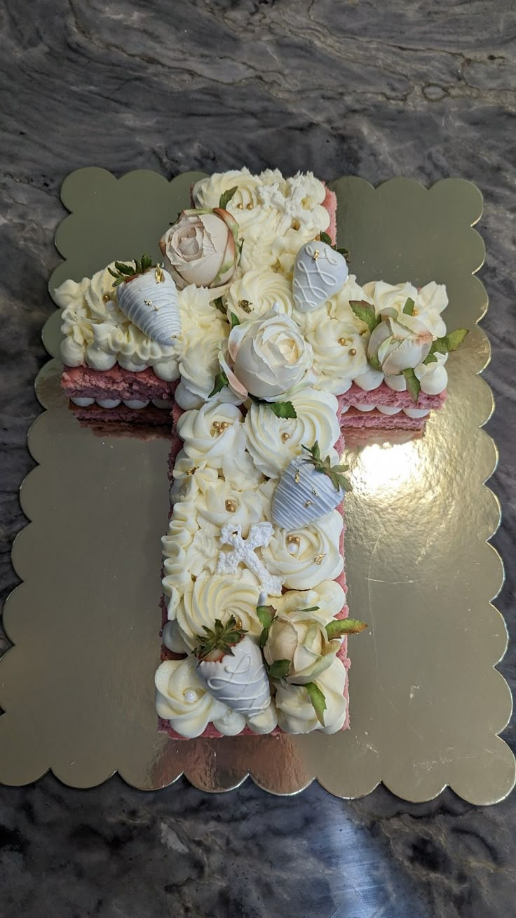 a cake shaped like a cross on top of a table covered in frosting and flowers