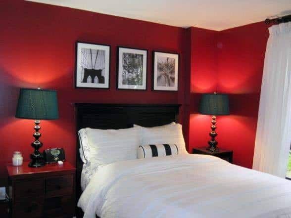 a bedroom with red walls and two lamps on either side of the bed in front of it