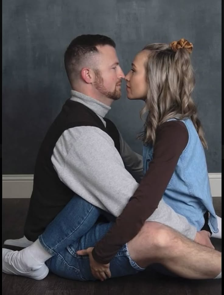 a man and woman sitting next to each other on the floor in front of a chalkboard wall