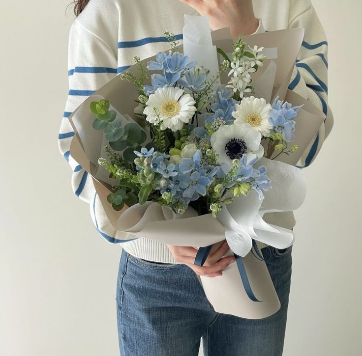 a woman holding a bouquet of blue and white flowers