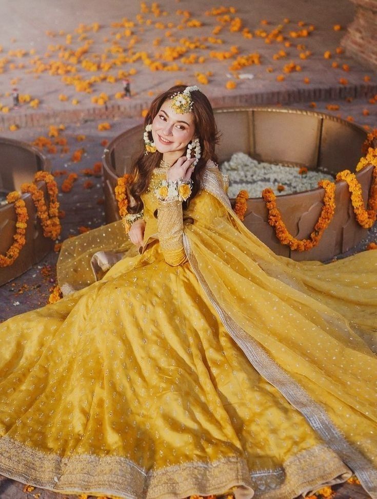 a woman in a yellow dress is sitting on a couch with flowers all around her