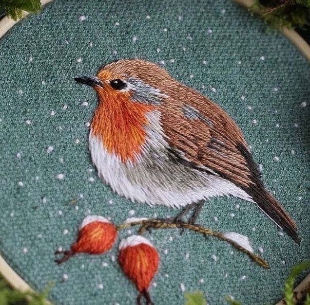 a cross stitched picture of a bird sitting on a branch with berries in the foreground