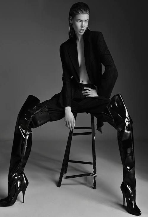 a woman sitting on top of a stool wearing high heeled boots and black pants