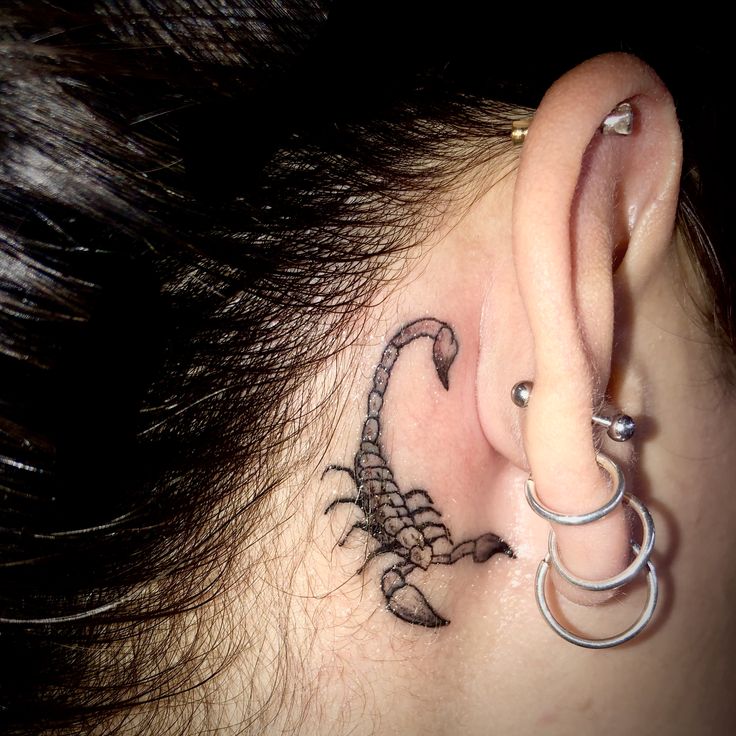 a woman's ear has a scorpion tattoo on it