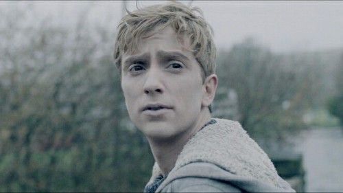 a young man is standing in front of some trees