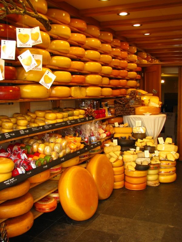 there are many different cheeses on display in the store, and one is yellow