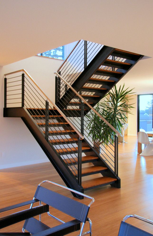 a living room filled with lots of furniture and a metal stair case next to a window