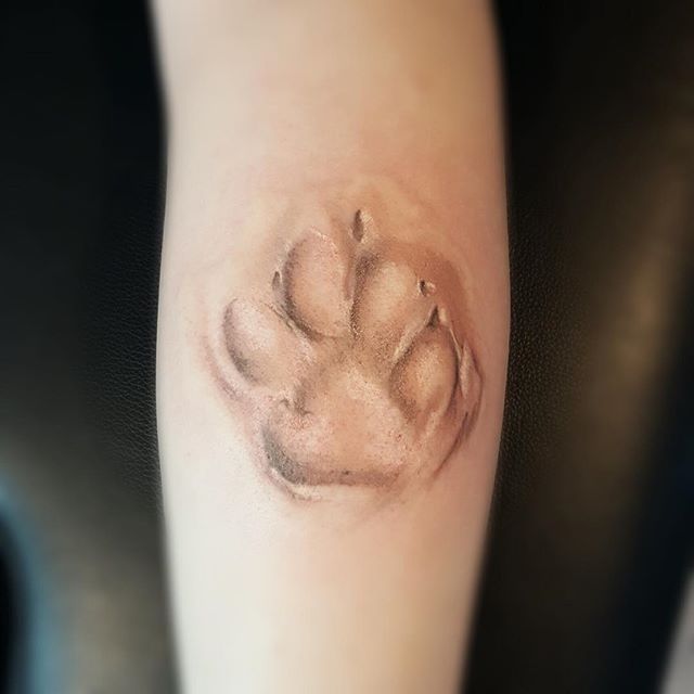 an animal paw tattoo on the right arm and left leg is shown in black and white