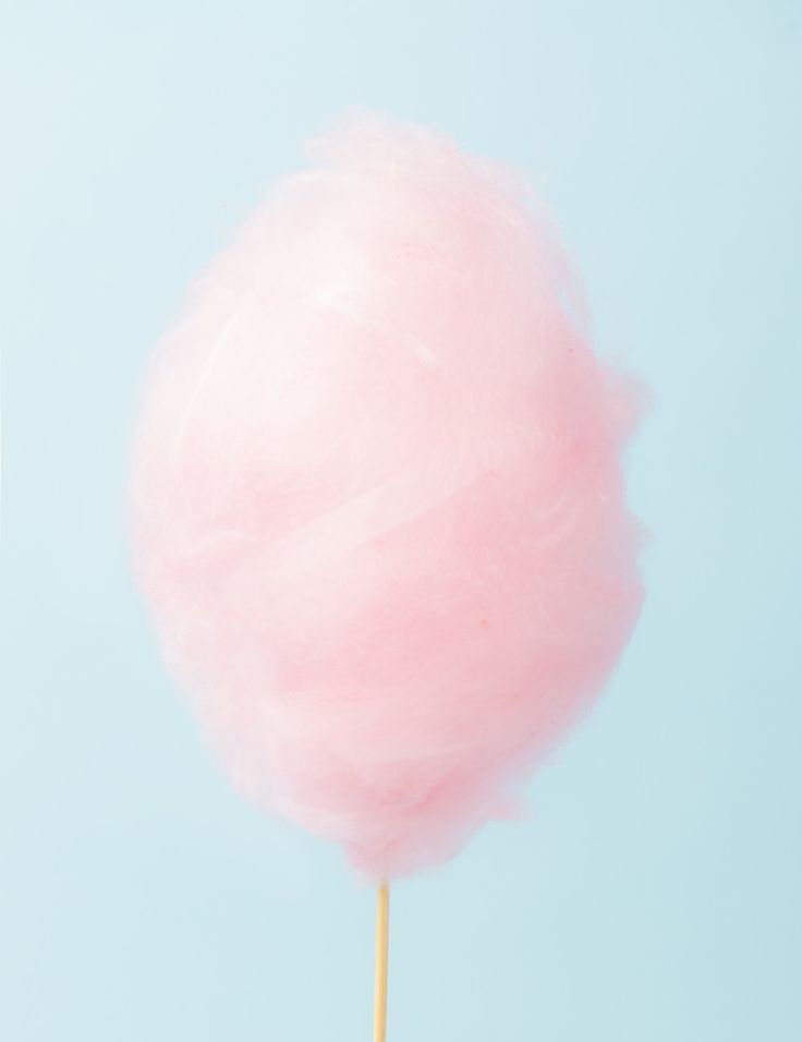 a pink cotton candy on a stick against a blue background