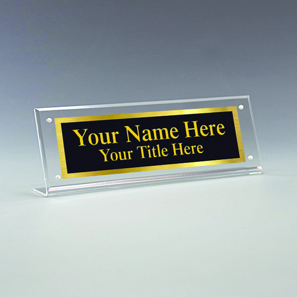 a clear acrylic sign that says your name here and has a gold border