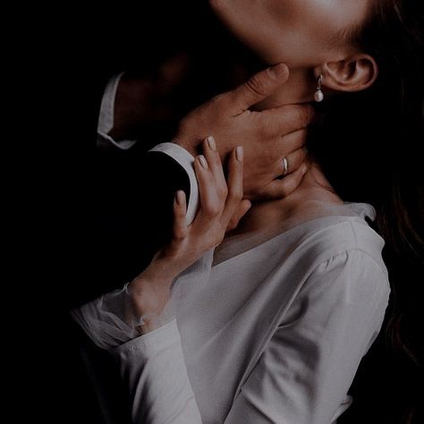 a man and woman kissing each other in front of a dark background with their hands on her chest