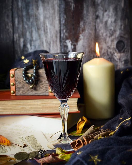 a glass of wine sitting on top of a table next to a candle and book