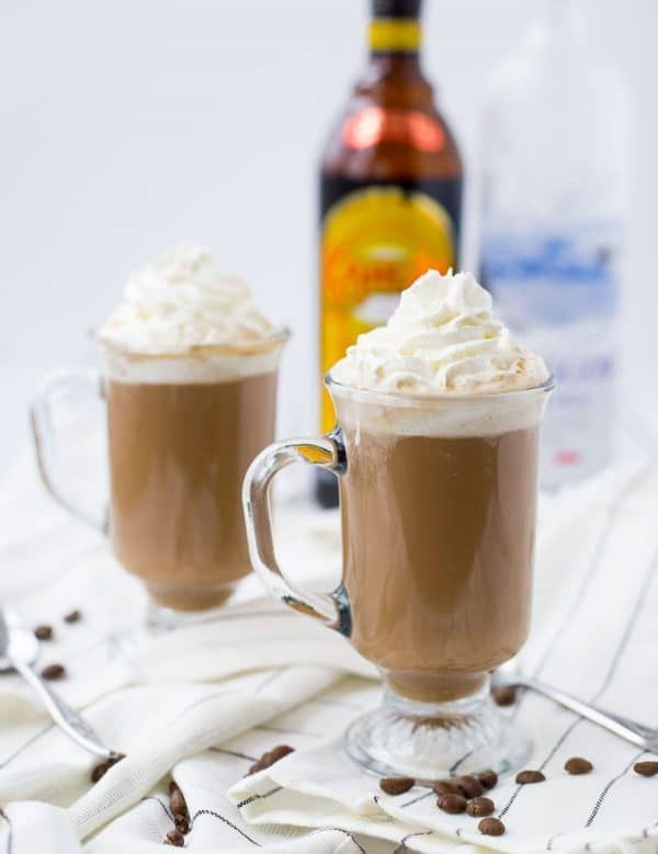 two mugs filled with hot chocolate and whipped cream sitting on top of a table